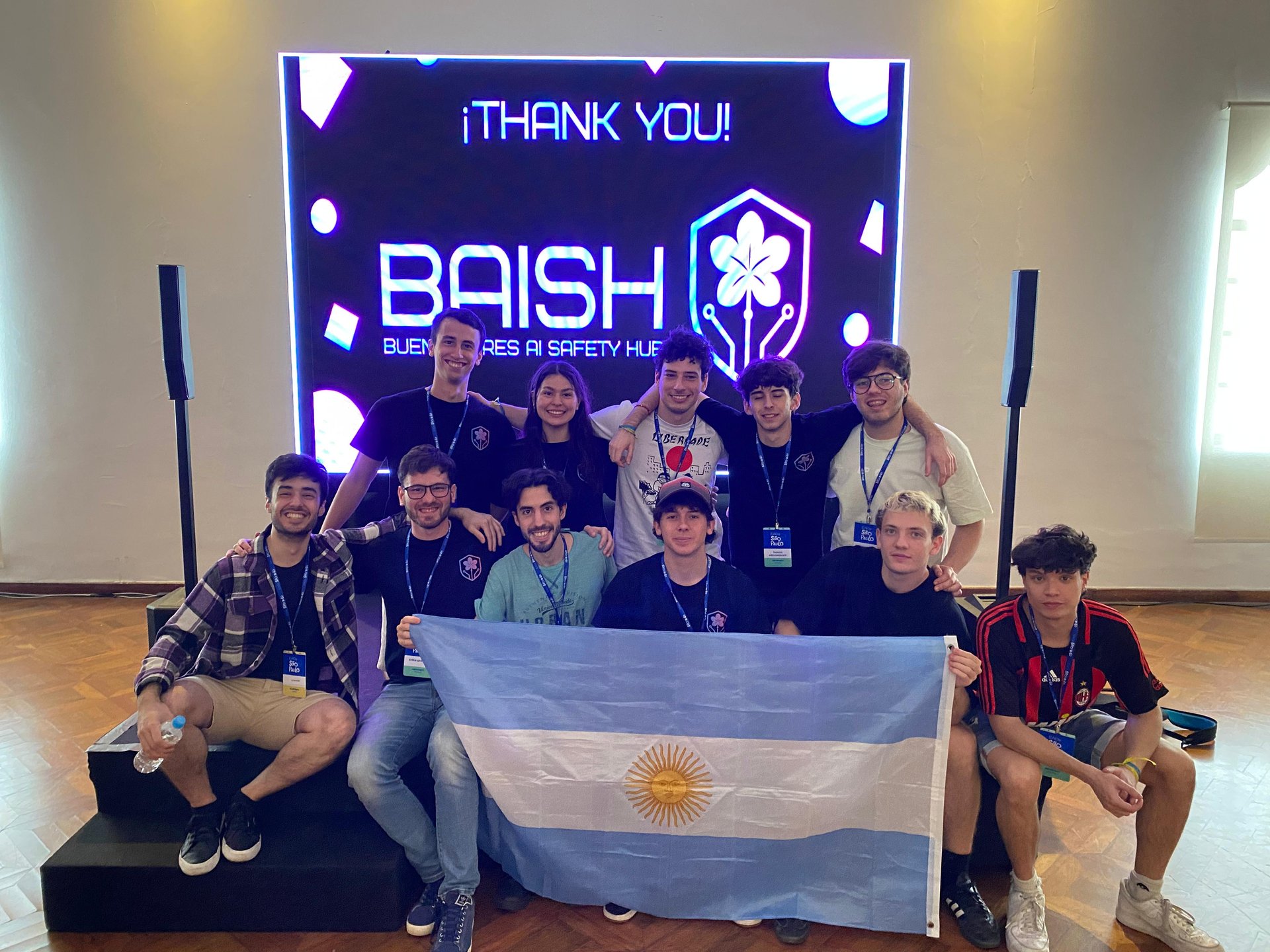 BAISH team photo with branding and Argentine flag at AI safety conference