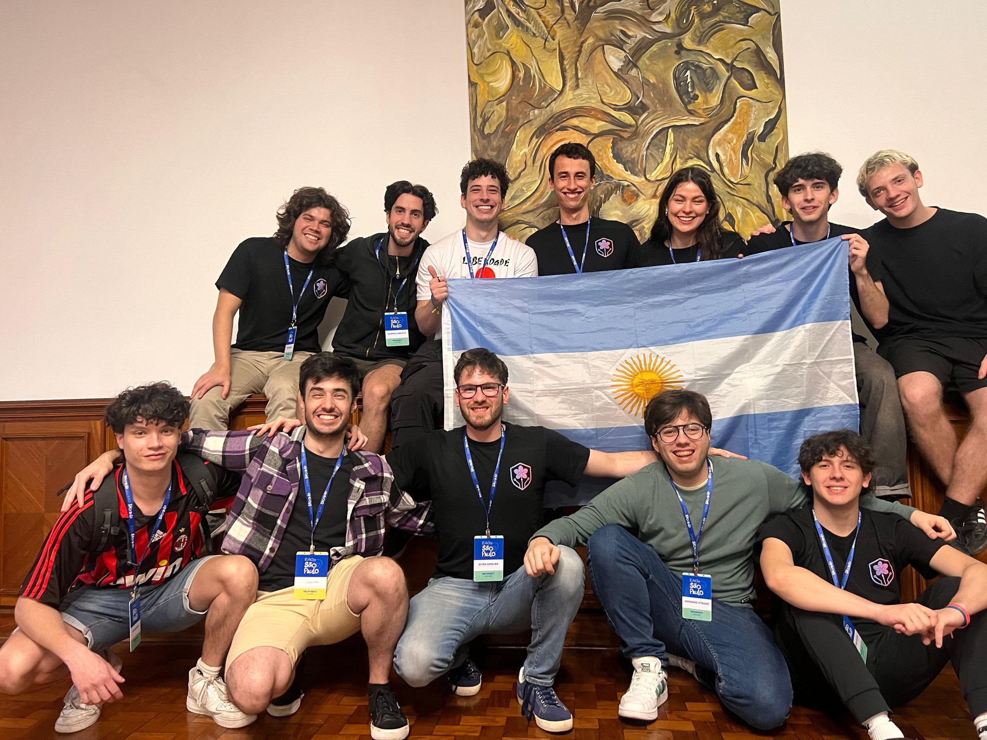 Team photo holding Argentine flag at international AI safety event